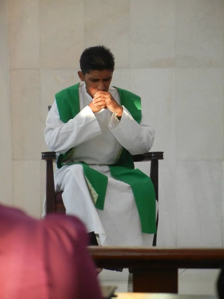 Rev. Fr. Stanley Antoni seated in prayer, wearing a green stole